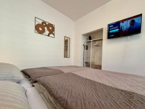 a bedroom with a bed and a flat screen tv at Apartment Leitha Living Cozy in Götzendorf an der Leitha