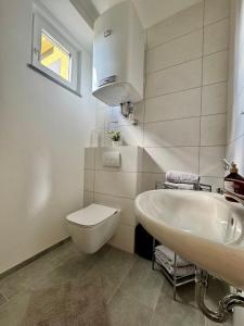 a white bathroom with a sink and a toilet at Apartment Leitha Living Cozy in Götzendorf an der Leitha