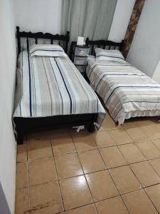 two beds in a room with a tile floor at Casa Amarilla hostel in Bajo Boquete