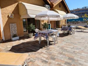 a patio with tables and umbrellas in front of a building at Casa Glicine in Finale Ligure