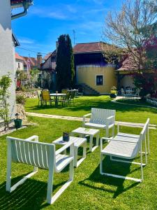 a group of white benches sitting on the grass at Apartments Dajčić in Varaždinske Toplice +94 photos