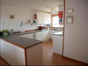 a kitchen with white cabinets and a black counter top at Ben Alder Spacious 3 Bedroom House in Orkney