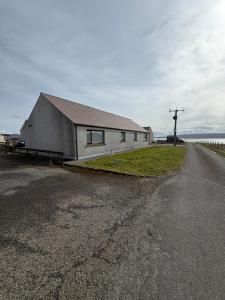 a building on the side of a road near the ocean at Ben Alder Spacious 3 Bedroom House in Orkney
