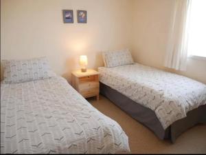 two beds in a bedroom with a lamp on a night stand at Ben Alder Spacious 3 Bedroom House in Orkney