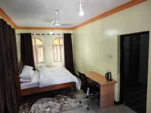 a bedroom with a bed and a desk and a window at Ocean Breeze Nook in Mombasa