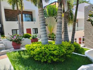 a garden with palm trees and flowers in front of a building at Condo arrosito village in Tangolunda