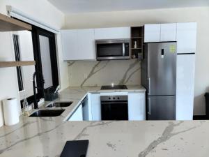 a kitchen with white cabinets and a stainless steel refrigerator at Condo arrosito village in Tangolunda