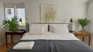 a bedroom with a large bed with white sheets and pillows at Cherry Tree House, Newlands in Cape Town