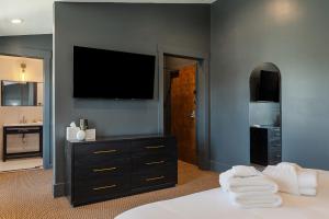 a bedroom with a black dresser and a television on a wall at Superior King Room at The Emerald in Beaufort