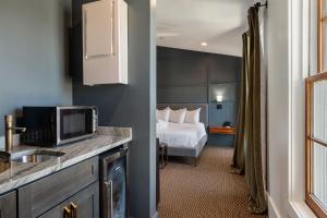 a hotel room with a bed and a kitchen with a microwave at Superior King Room at The Emerald in Beaufort