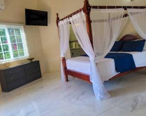 a bedroom with a bed with a canopy at Home Escape Negril Unit 3 in Negril