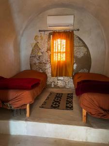 a room with two beds and a window with a heater at L'Oasis Zarga in Qaşr Ghīlān
