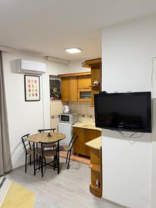 a small kitchen with a table and a kitchen with a tv at Spring Studio Apartment in Prizren