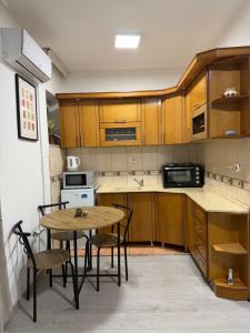 a kitchen with wooden cabinets and a table and chairs at Spring Studio Apartment in Prizren
