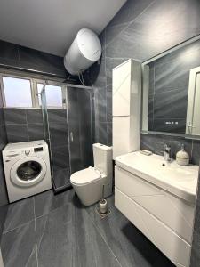 a bathroom with a toilet and a sink and a washing machine at Spring Studio Apartment in Prizren