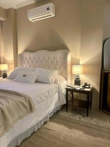 a bedroom with a large white bed and a night stand at Hotel Ibicui in Rosário do Sul
