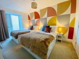 two beds in a room with a colorful wall at Superb House Sleeps 7 parking in Cambridge in Trumpington
