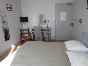 a bedroom with a bed and a desk with a television at Les Chambres du Phoebus in La Tremblade