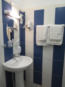 a bathroom with a sink and a mirror and towels at Les Chambres du Phoebus in La Tremblade