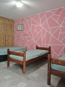 a room with two beds and a pink wall at Casa da mãe joanna in Guapimirim