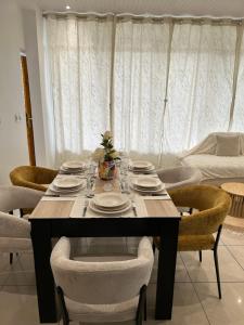 a dining room table with chairs and plates on it at Le Papillon in Le Moule
