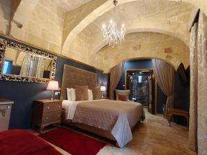 a bedroom with a large bed and a chandelier at Julina Boutique Living in Mosta