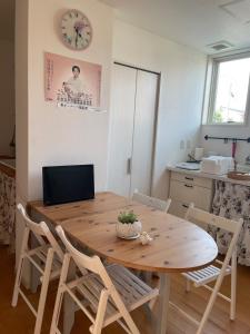 a dining room table with chairs and a clock on the wall at ReFa room由来House in Kumamoto