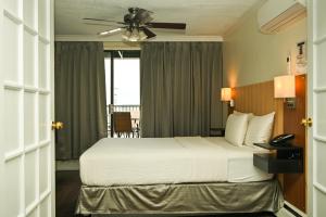 a bedroom with a large bed with a ceiling fan at Hotel Opportune in Vancouver