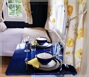 a table with plates and bowls and glasses on it at Shepherd's Hut near Oxford in Cumnor