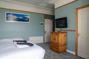 a bedroom with a bed and a flat screen tv at Harbour Heights B&B in Portrush +54 photos