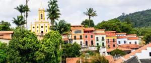 a group of buildings with a clock tower and trees at Flat Guaramiranga - Apto 201 in Guaramiranga