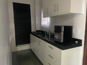 a kitchen with white cabinets and a black counter top at Residencial Mandi in Guaíra