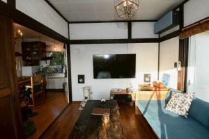 a living room with a couch and a tv on a wall at VILLE Noble Savage see view薪ストーブサウナ付き in Minamiizu