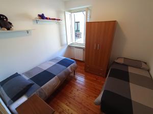 a bedroom with two beds and a cabinet and a window at Appartamento Palazzo Gattolini Venzone in Venzone