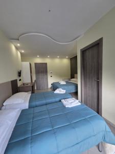 two beds in a hotel room with blue sheets at Hotel Rodian in Acquappesa