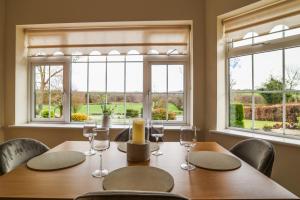 a dining room with a table with chairs and windows at Hillside House- Pine View in Ballinamuck