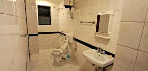 a white bathroom with a toilet and a sink at Shillong Serviced Apartment in Shillong +6 photos