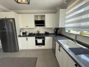 a kitchen with white cabinets and a stainless steel refrigerator at Villa Atay in Dalyan