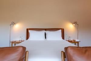 a bedroom with a large bed with two chairs at DOURWIN Exclusive Suites & Restaurant - Adults Only in Sebolido
