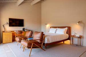a hotel room with a bed and two chairs at DOURWIN Exclusive Suites & Restaurant - Adults Only in Sebolido