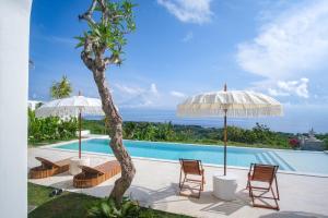 a view of a pool with chairs and umbrellas at Villa Kai Nusa Penida in Sampalan