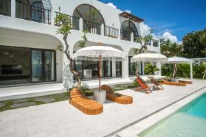 a house with chairs and umbrellas next to a swimming pool at Villa Kai Nusa Penida in Sampalan