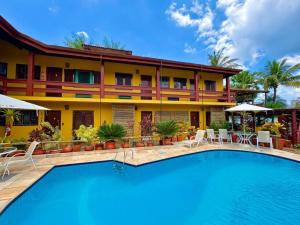 a hotel with a swimming pool in front of a building at Residencial Villa Cris - Jd. São Lourenço/Itaguaré in Bertioga