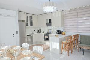 a kitchen with white cabinets and a table and chairs at Vıllaozden in Belek