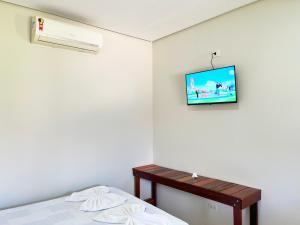 a room with a bed and a tv on the wall at Pousada Elizium in Montes Claros