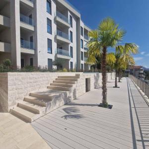a sidewalk in front of a building with palm trees at Olive residence A8 in Petrovac na Moru