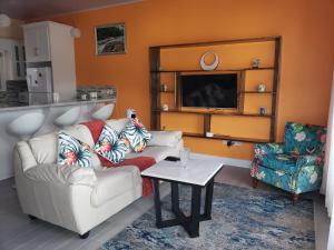 a living room with a couch and a table and a tv at JemmRose Suites in Choc