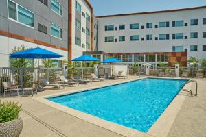 a swimming pool with chairs and umbrellas and a building at Element by Marriott San Diego Chula Vista in Chula Vista
