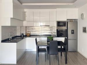 a kitchen with white cabinets and a table and chairs at Modern 2-bdr apt with rooftop pool - LCGR in Praia