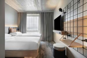 a hotel room with two beds and a television at Moxy Aarhus in Aarhus